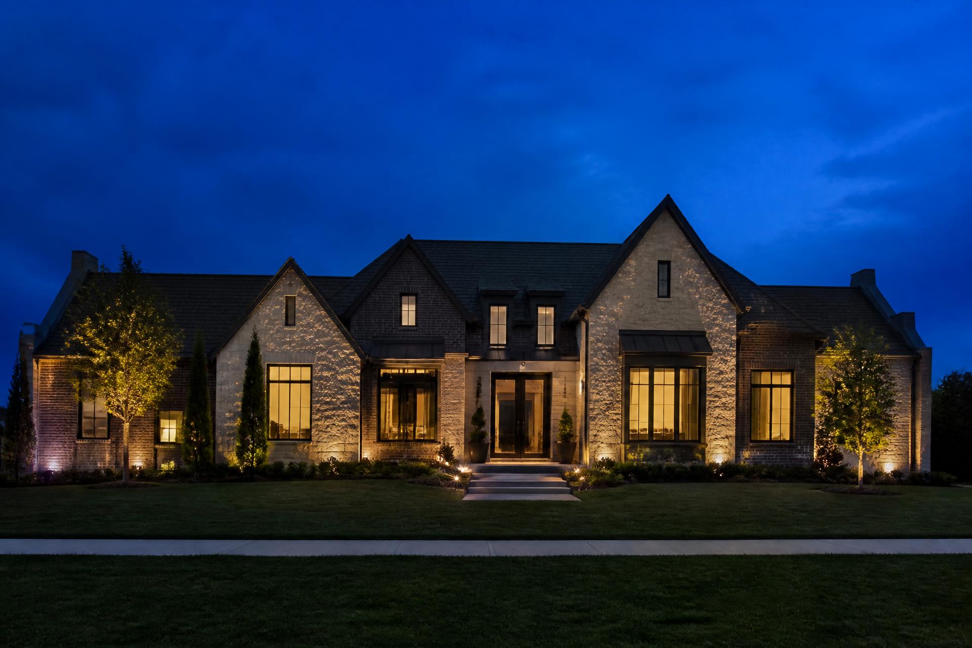 Upscale single-family home at blue hour with warm interior lighting